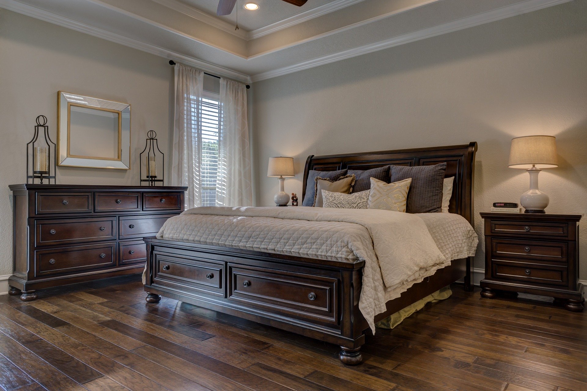 Bedroom with dark wood bedroom set consisting of a king sized bed, night stand, and chest of drawers