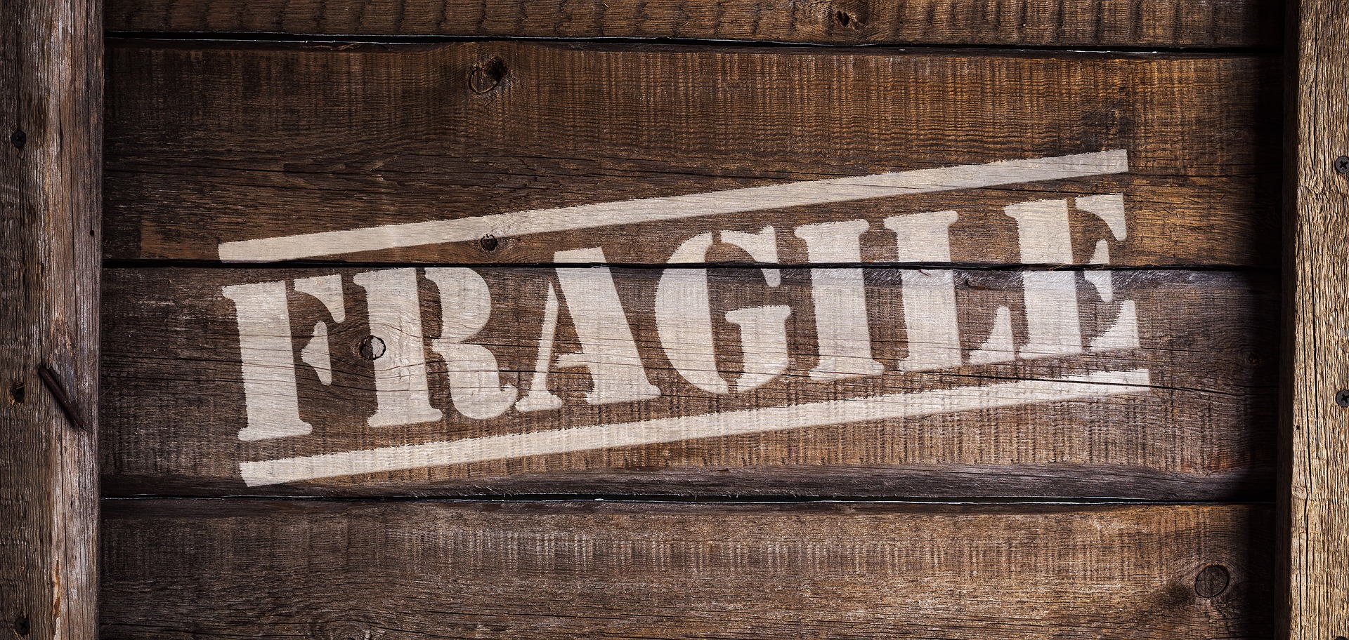 side of a wooden box that has the word "fragile" spray painted on it in white