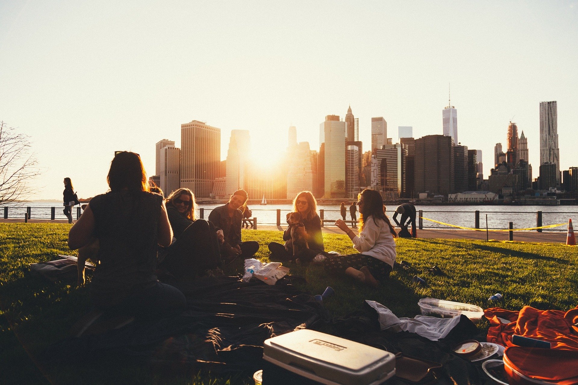 group of people having a picnic in Brooklyn Bridge Park overlooking lower Manhattan.