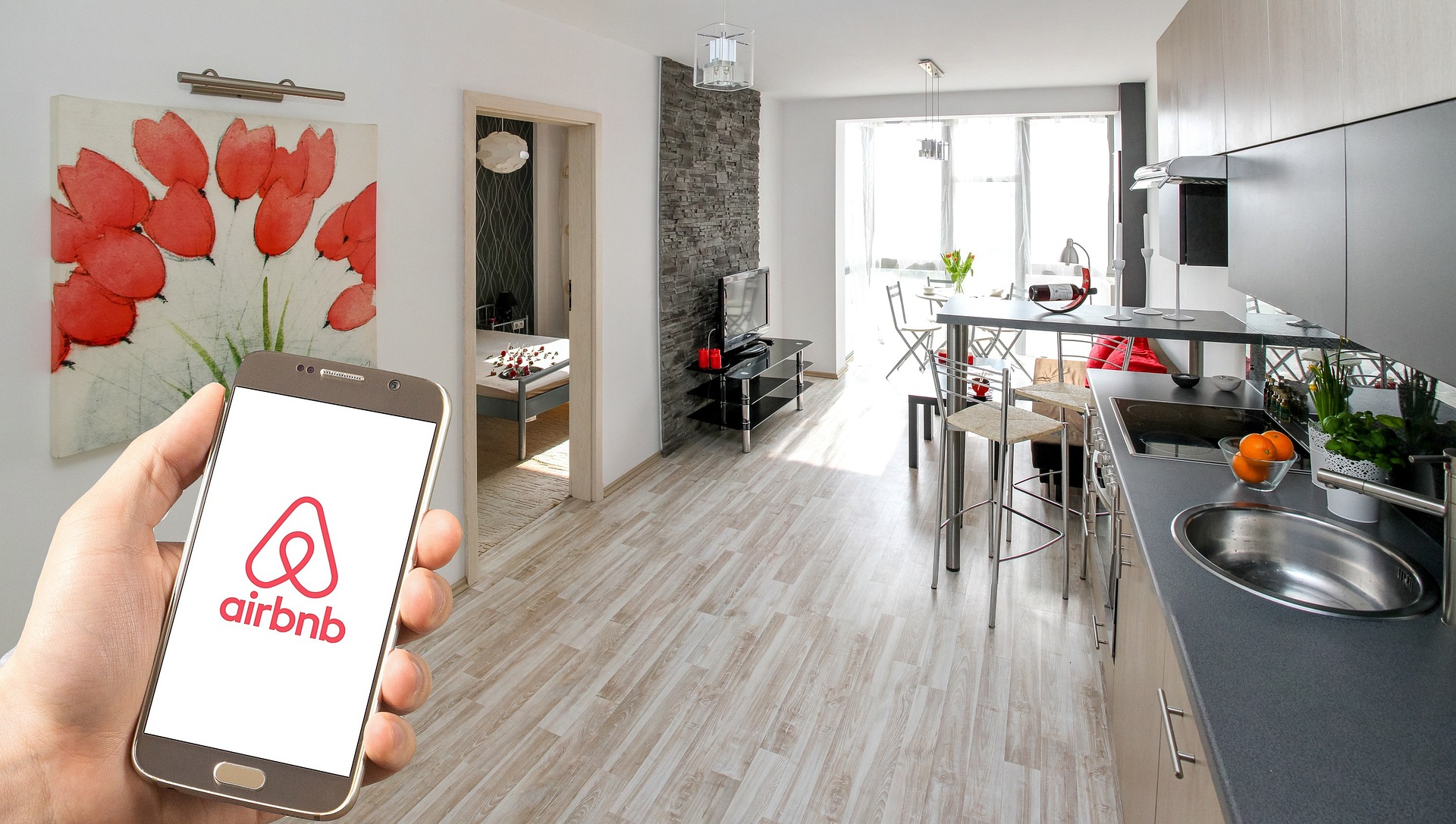 An airbnb unit with a person holding a phone showing the airbnb logo