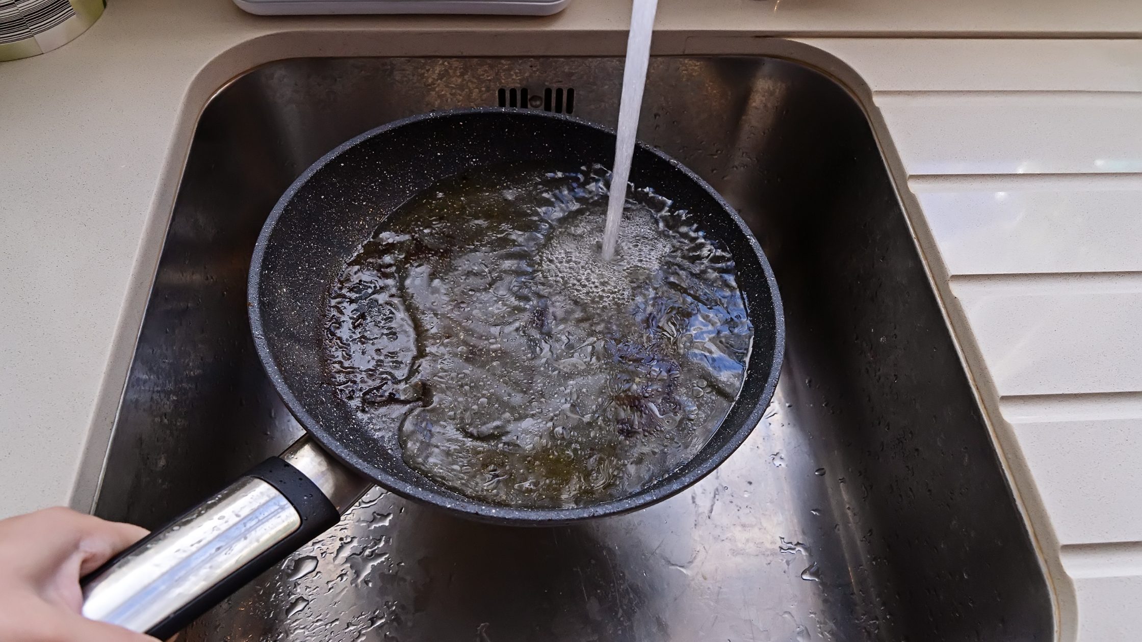 greasy pan being washed in sink