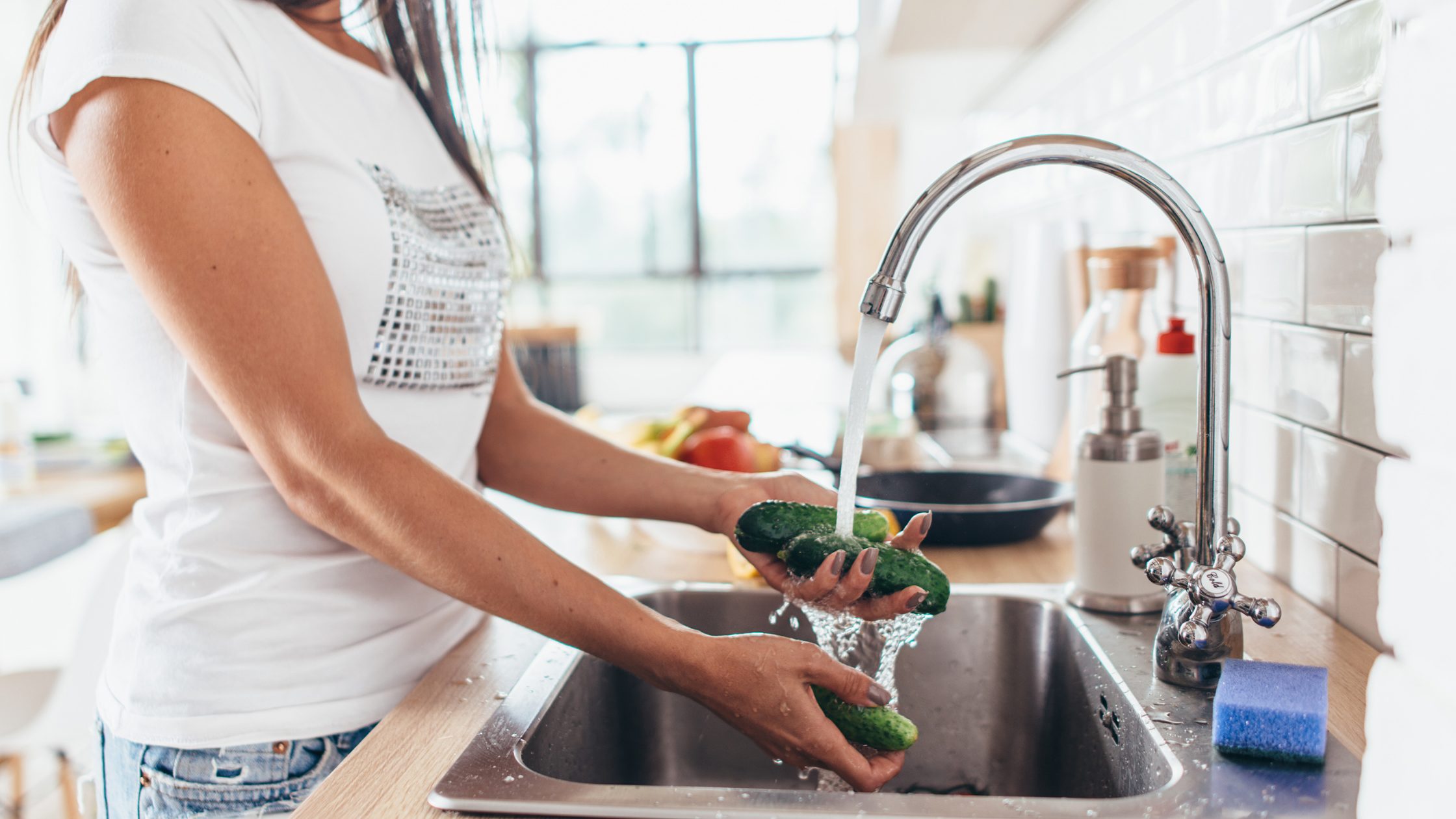woman washing vegetables in sink