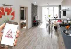 An airbnb unit with a person holding a phone showing the airbnb logo